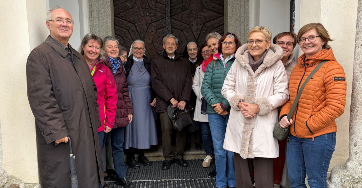 Gruppe aus Frauen und Männern (Ehrenamtliche, Schwestern, Monsignore) vor dem Kircheneingang
